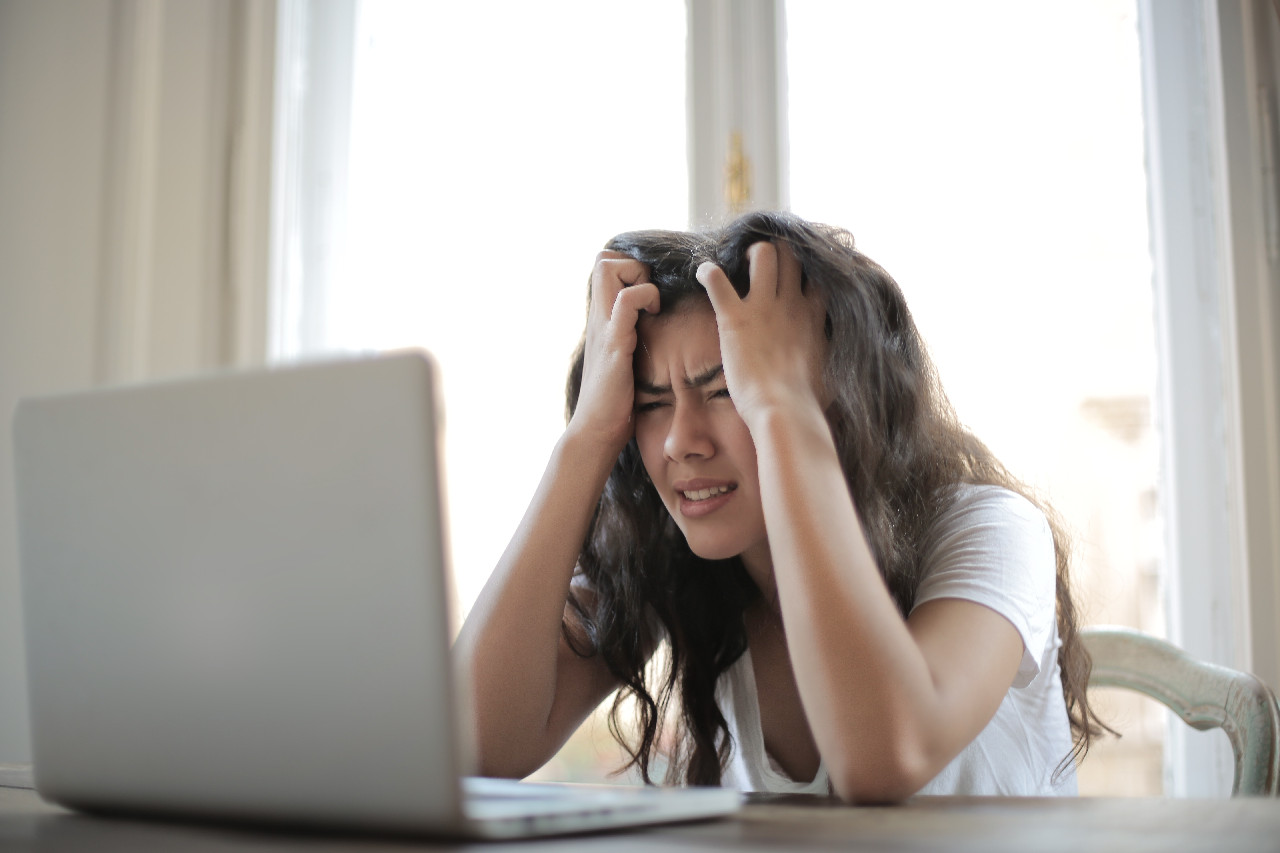 woman sitting in front of laptop showing frustration